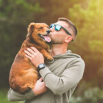 Man holding dog in his arms and kissing him outdoors. Dog and owner together. Love for pets. High quality photo